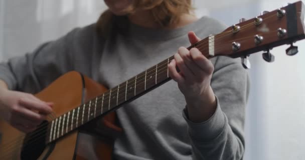 Teenager hraje na kytaru v jasném obývacím pokoji s krásným slunečním světlem. Žena skládá hudbu uvnitř. Umělec hraje na akustickou kytaru. Ta holka si sama hraje na hudební nástroj.. — Stock video