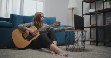 Öğrenci bir dizüstü bilgisayardan online ders izlemeye başlar. Kız elinde bir müzik aleti tutuyordu. Genç bir müzisyen parmaklarıyla gitarın tellerine basıyor..