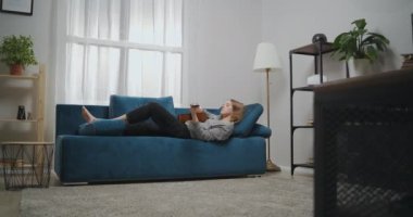 Gündelik giysiler içinde genç bir kız modern bir oturma odasındaki bir kanepede yalınayak yatıyor. O, akustik bir gitarda romantik müzik çalar. Düşük ihtimal.