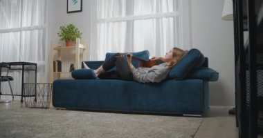 Gündelik giysiler içinde genç bir kız modern bir oturma odasındaki bir kanepede yalınayak yatıyor. O, akustik bir gitarda romantik müzik çalar..