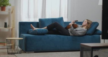 Gündelik giysiler içinde çekici bir genç kız evde gitar çalar. Mavi bir koltukta dinlenen kadın gitarist bir müzik aletine bakıyor. Düşük ihtimal.