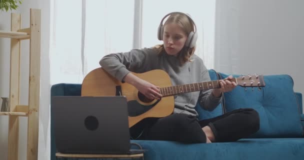 Bir genç gitarda iki akor öğrenir. Kulaklıklı bir kadın müzikal bir melodi yakalıyor.. — Stok video