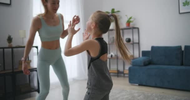 Neşeli anne ve kızı spor eğitiminden sonra apartman dairesinde kör adamı oynuyorlar. — Stok video