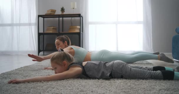 Home fitness training of sporty family, mother and daughter are training together in living room, gymnastics — Stock Video