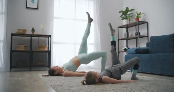 Спортивна дочка і мати тренуються разом вдома, жінка вчить свою дитину робити фізичні вправи — стокове відео