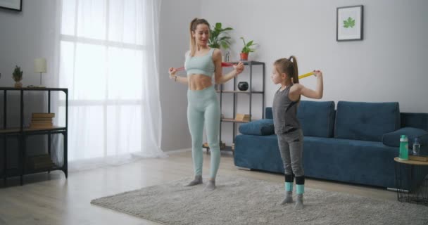 苗条的女运动员正在家里训练她的小女儿，给孩子灌输好习惯和健康的生活方式 — 图库视频影像