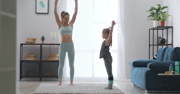 Moeder en dochter doen fitnessoefeningen met sportieve elastische band thuis, ochtendtraining — Stockvideo