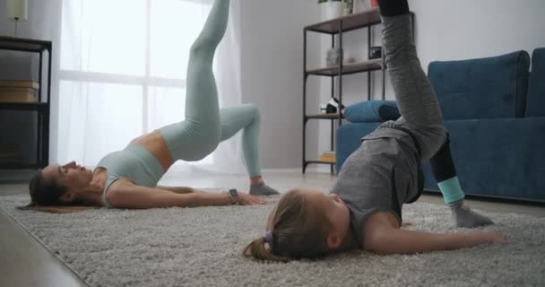 Mère sportive forme sa petite fille à la maison, maman et sa fille font des asanas de yoga et des exercices physiques — Video