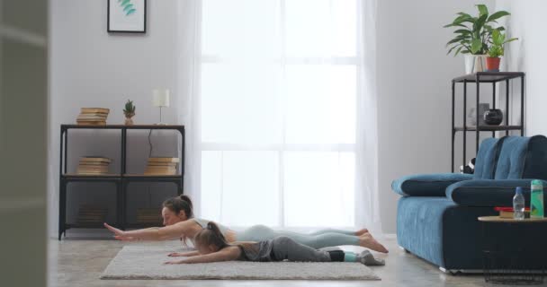 Familia sportivă se antrenează în apartament în weekend, mama și fiica stau întinse pe podea și fac exerciții fizice, un stil de viață sănătos — Videoclip de stoc