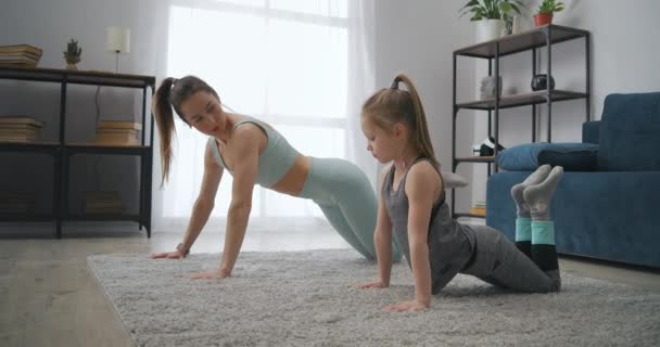 Little girl is learning to do push-ups with her mother, home fitness for family, sport activity and healthy lifestyle, mommy and daughter — Stock Video