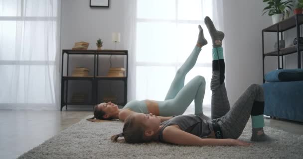 Спортивна діяльність молодої матері і маленької дівчинки вдома, тренування разом в квартирі, виконання йоги асан — стокове відео