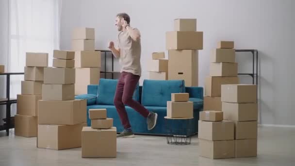 Young man have fun dancing in their new home. Very Happy Man Moves Into His New Apartment, Dances Excited. Guy Purchased New Home Ready to Start Unpacking Cardboard Boxes. — Stock Video