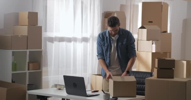 Hombre abre caja de cartón con un cuchillo clerical. El hombre saca las gafas VR de la caja. Largo plazo. — Vídeos de Stock