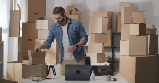 商人把货物放在一个纸板箱里.3.小伙子正在把商品折叠起来寄给顾客. — 图库视频影像