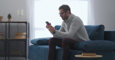 Akıllı adam internette haberleri akıllı telefondan okuyor, evde tek başına oturuyor, internette ve sosyal ağlarda sörf yapıyor.