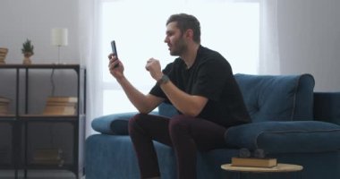 Yetişkin adam, spor etkinliklerinin internet çevirisi, akıllı telefon ve internet üzerinden maç izliyor.
