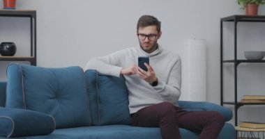 Erkek kullanıcı akıllı telefonuyla uygulama ya da internet sitesinde piyango oynuyor ve kazananın duygusal sevinçlerini kazanıyor.