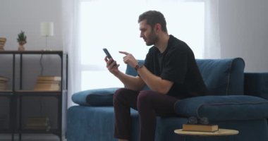 Yetişkin bir adamın piyangoda kazandığı coşkulu neşe ve sevinç, akıllı telefondan haberleri izlemek ve duygusal olarak sevinç.
