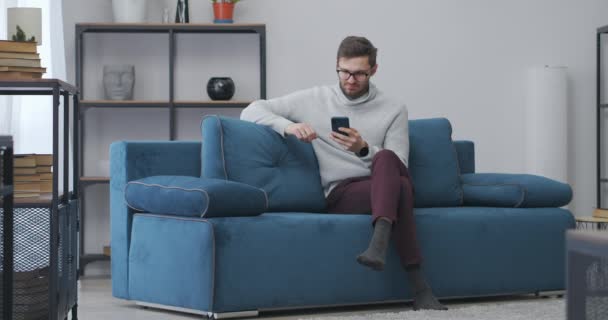 Man speelt spel in smartphone en winnen, vreugde door te winnen, emotioneel portret van volwassen man in appartement — Stockvideo