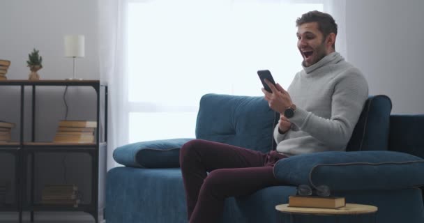 Homem alegre está lendo notícias no smartphone, emoção de ganhar e felicidade, pessoa está se alegrando emocionalmente — Vídeo de Stock