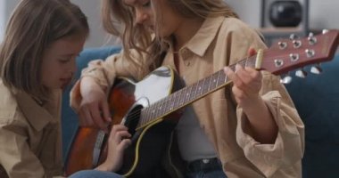 Anne, anaokulu kızına gitar çalmayı öğretiyor. Hafta sonları evde birlikte vakit geçiriyorlar.