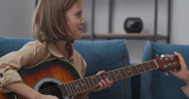 Mutlu anne ve kız gitar oyunu hakkında iletişim kuruyor, kadın küçük kızı övüyor, başparmağını gösteriyor.