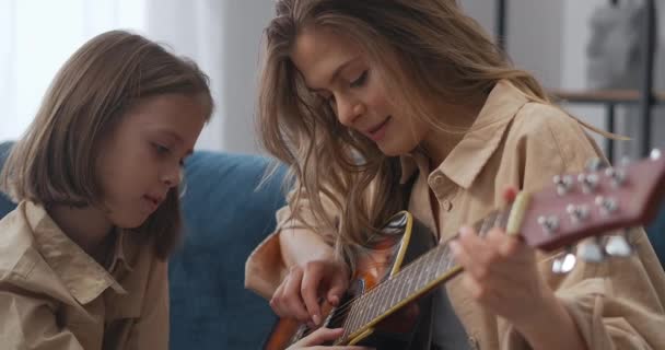 Šťastné okamžiky dětství a mateřství, žena učí svou dceru hrát na kytaru, veselé tváře — Stock video