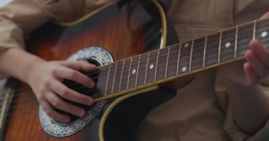 Gitar küçük kızın elinde, çocuk müzik çalmayı öğreniyor, eğitiyor ve tellere dokunmaya çalışıyor, liseli kız için müzik dersi.
