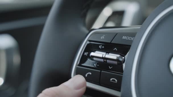 Cierre del dedo presionando los botones de control de audio para aumentar o disminuir el volumen en el volante al conducir. Volumen de audio del volante ajustar — Vídeo de stock