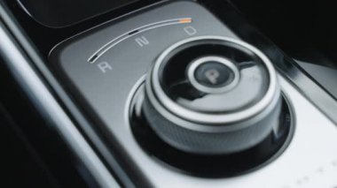 Yakından bakan adam otomatik vites kutusunun şanzımanını değiştiriyor. Park, sürüş, geri vites. Erkek sürücünün yakın çekimi otomatik vites kolunu park yerinden sürücü koltuğuna çevirir.