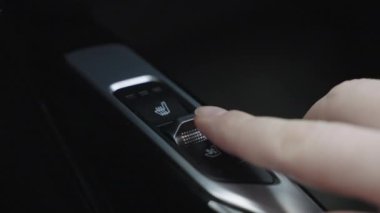 Araba panelindeki düğmeye basan adama yakın çekim. Arabada ısıtma için düğme. Adam ısıtmalı koltukları açıyor..