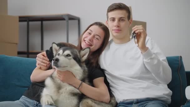Een jonge man streelt zijn mooie vrouw op de schouder. Een vrolijke vrouw krabt aan haar hond. Het echtpaar verhuisde naar een nieuw huis. — Stockvideo