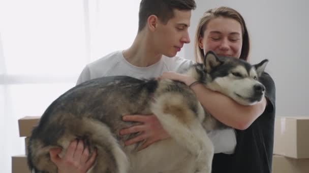 Um plano de perto. Um homem tem um animal de estimação nos braços. Uma namorada alegre abraça seu cão amado. — Vídeo de Stock
