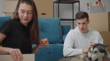 Hafif kazaklı ince bir adam köpeğinin kafasını okşar. Güzel bir kadın bir karton kutunun içindekilere bakar ve sonra onu bir kenara atar. Yeni bir yaşam alanına taşınıyorum..