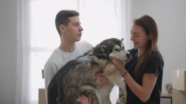 Yakın plan çekim. Bir adam yetişkin bir köpeği kollarında tutuyor. Genç bir kadın sevgili köpeğini okşuyor. Mutlu aile yaşam alanını genişletir..