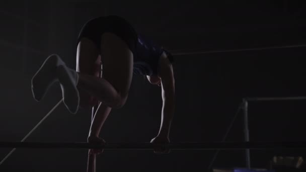 Junior kvinnliga gymnast utför på ojämn barer i sporthall, tonåring sportig flicka gör övningar på apparater — Stockvideo
