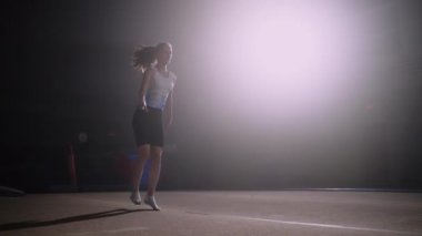 Genç atletik kız jimnastik salonunda antrenman yapıyor, yer egzersizi yapıyor, bahar zemininde zıplıyor.