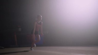 Genç bayan artistik jimnastikçi eğitimi. Genç kız koşuyor, zıplıyor, takla atıyor.