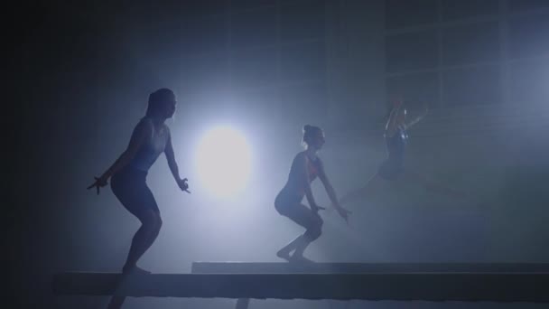 Женская команда по спортивной гимнастике выступает на бревне, спортсмены тренируются вместе — стоковое видео