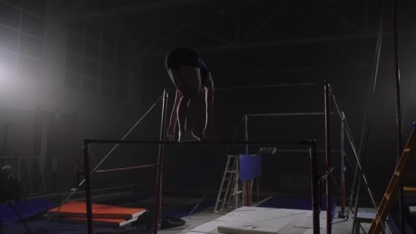 Tonåring flicka uppträder på ojämn barer i gymnastiksal, tonåring gymnast på konkurrens av konstnärlig gymnastik — Stockvideo