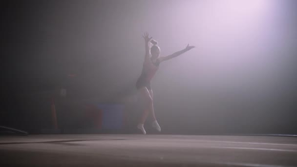 Юношеские женские соревнования по художественной гимнастике, юная девушка выступает на полу, гимнастка делает сальто — стоковое видео