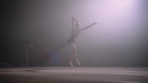 Junior female competitions of artistic gymnastics, young girl is performing on floor, gymnast is doing somersault — Stock Video