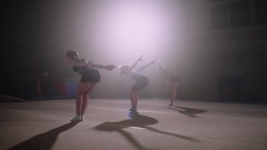 Bir grup genç bayan jimnastikçi spor salonunda ters takla atıyor.