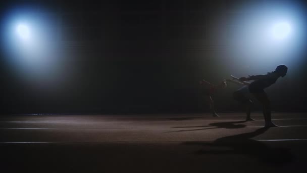 Drie sportieve meisjes doen backflip synchroon in sporthal, vloer oefening van artistieke gymnastiek, slow motion shot — Stockvideo