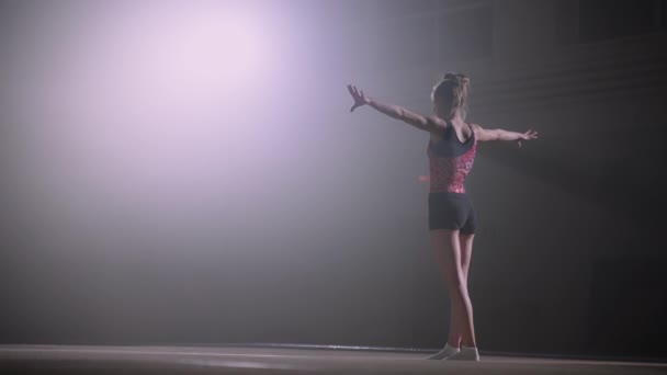 Júnior ginasta feminino está de pé no chão, preparando-se para começar a exercer, treinamento ou competição — Vídeo de Stock