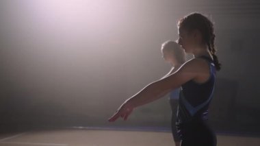 Üç ergen kız, sanatsal veya ritmik jimnastik müsabakalarına hazırlanmak için yer egzersizleri yapıyor.