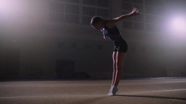 Genç yetenekli sporcu kız jimnastik salonunda ters takla atıyor. Sanatsal jimnastik yarışmasına hazırlanıyor.