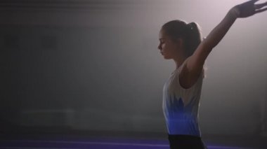 Genç kız spor salonunda taklalar atıyor, spor salonunda antrenman yapıyor, yer egzersizleri yapıyor.