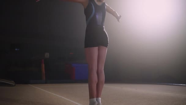 Младшая гимнастка выполняет сальто в спортзале, соревнование по художественной гимнастике — стоковое видео