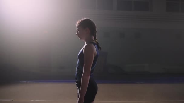 Skolflicka med flätor är träning ensam i sporthall, utför golv motion, två flip back — Stockvideo